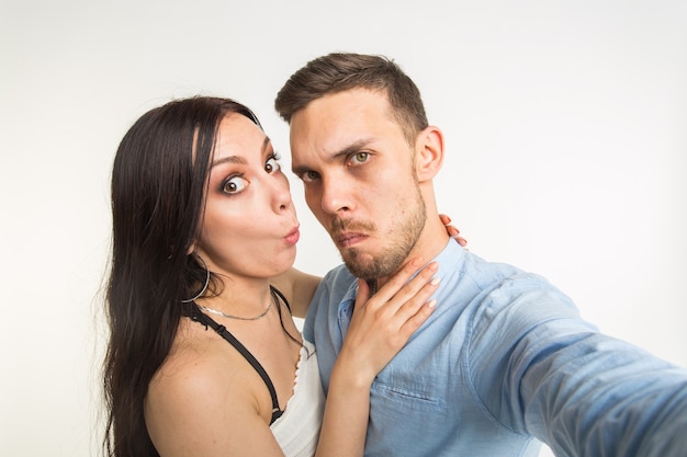 Concept de relation et de famille - heureux couple drôle prenant selfie sur fond blanc.