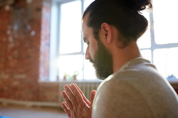 concept de religion, de foi et de personnes - gros plan d'une femme méditant ou priant au studio de yoga