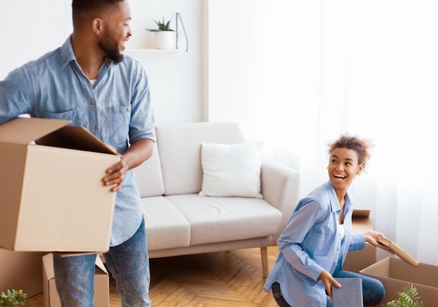 Le concept de relocalisation excite un jeune couple afro qui emballent des boîtes de déménagement à l'intérieur.