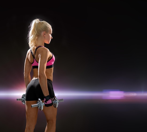 concept de remise en forme, d'exercice et de régime - femme sportive avec des haltères en acier lourd de l'arrière