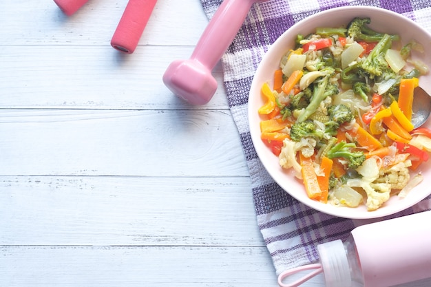 Concept de remise en forme avec haltère, légumes frais et ruban de mesure sur rose