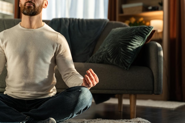 Concept de remise en forme, de méditation et de mode de vie sain. Homme de race blanche méditant en posture de lotus à la maison