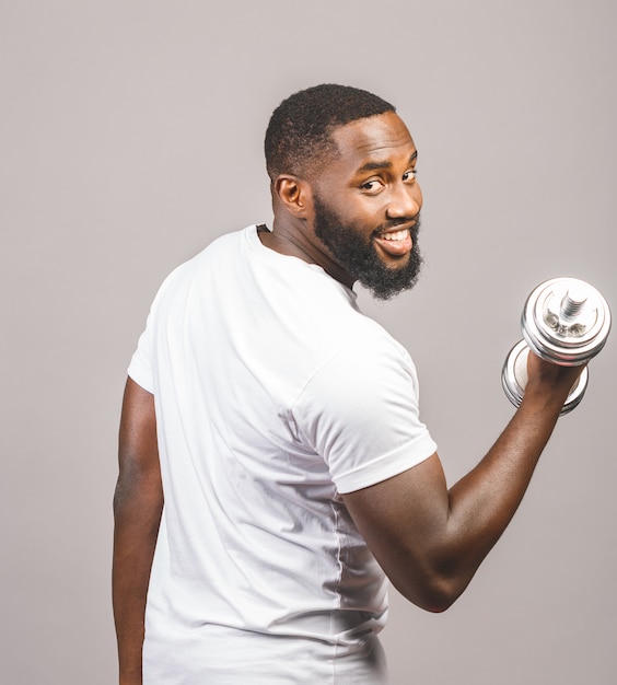 Concept de remise en forme. Portrait d'un homme noir afro-américain heureux avec des haltères isolés sur fond gris.