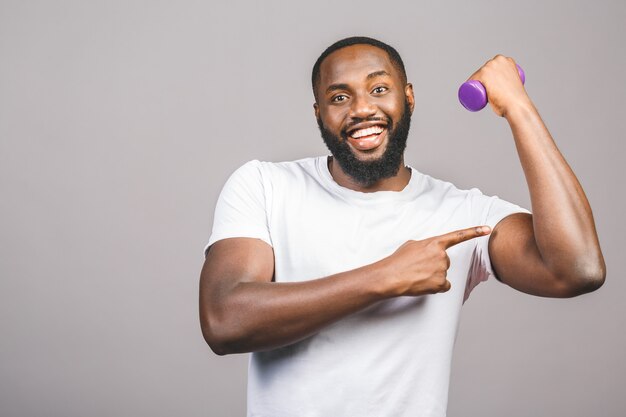 Concept de remise en forme. Portrait d'un homme noir afro-américain heureux avec des haltères isolés sur fond gris.