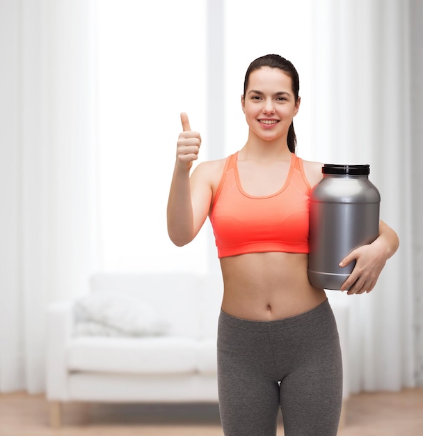 concept de remise en forme et de régime - adolescente souriante avec pot de protéines montrant les pouces vers le haut