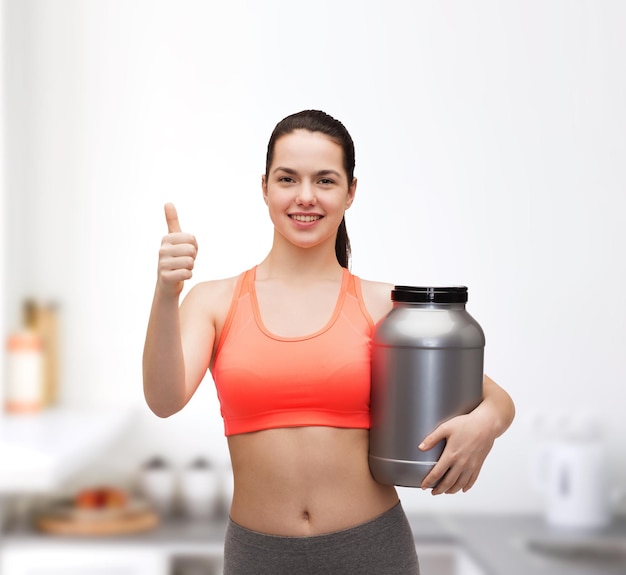 concept de remise en forme et de régime - adolescente souriante avec pot de protéines montrant les pouces vers le haut