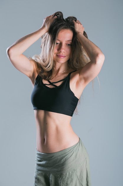 Concept de remise en forme et de régime. Portrait de jeune femme avec un corps sportif parfait et des abdos assez plats en haut de sportswear sexy sur fond gris.