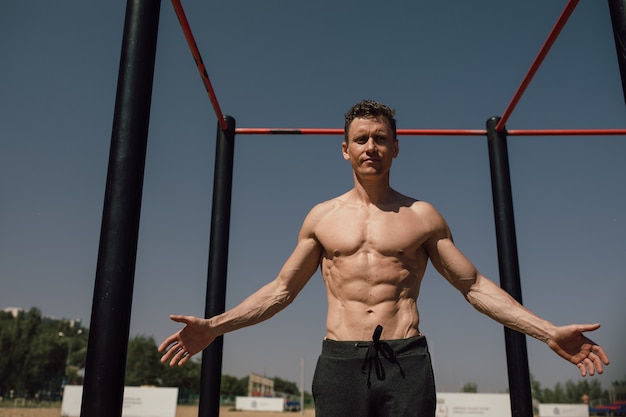 Concept de remise en forme, sport, entraînement et mode de vie - jeune homme exerçant sur une barre horizontale sur la plage. photo de haute qualité