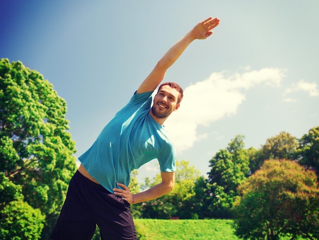 concept de remise en forme, de sport, d'entraînement et de style de vie - homme souriant étirant la main à l'extérieur