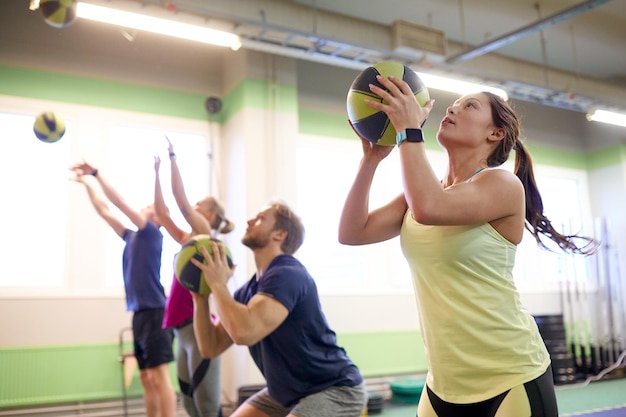 concept de remise en forme, de sport et d'exercice - groupe de personnes avec des ballons médicinaux s'entraînant dans une salle de sport