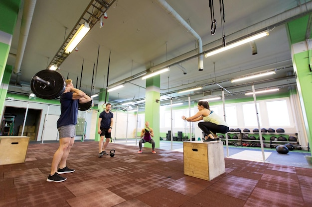 concept de remise en forme, de sport et d'exercice - groupe de personnes s'entraînant avec différents équipements dans une salle de sport