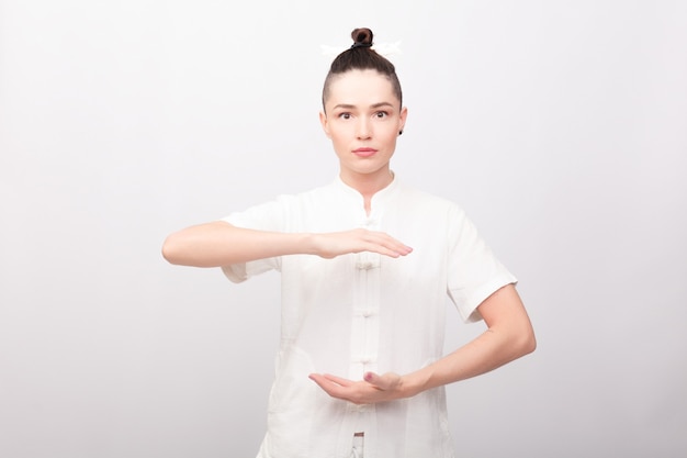 Concept de remise en forme, sport, formation et mode de vie - jeune femme faisant des exercices d'yoga. Jeune femme pratiquant le tai chi chuan dans la salle de gym. Compétence de gestion chinoise Énergie de Qi.