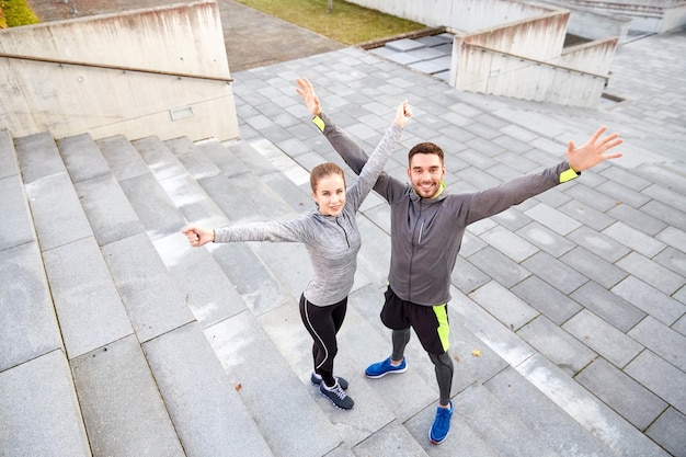 concept de remise en forme, de sport, de personnes et de style de vie - couple souriant heureux à l'extérieur dans la rue de la ville