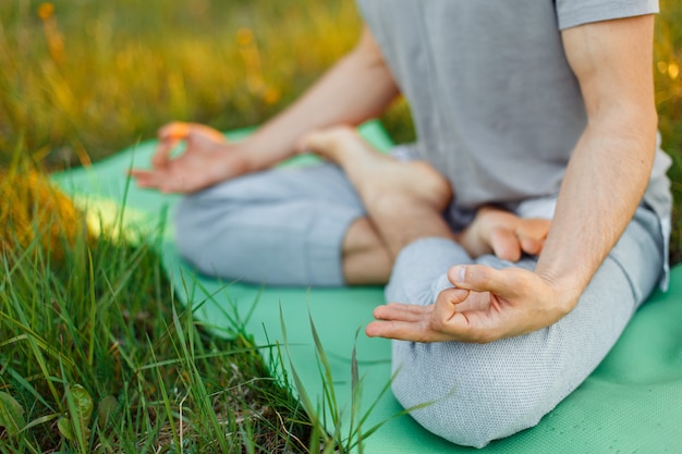 Concept de remise en forme, sport, yoga et mode de vie sain - gros plan de personnes méditant en position assise facile dans le parc ou le jardin