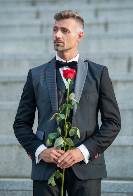 Concept de rendez-vous d'amour homme de smoking adulte avec cadeau de fleur de rose d'amour pour la journée de l'amour