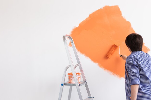 Concept de rénovation, redécoration et réparation - mur de peinture femme d'âge moyen dans une nouvelle maison.