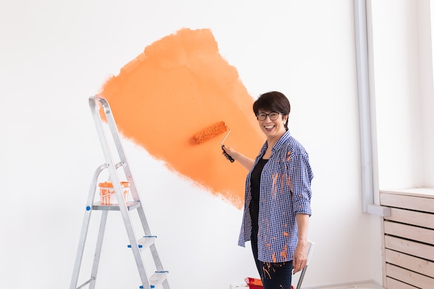 Concept de rénovation, redécoration et réparation - mur de peinture femme d'âge moyen dans une nouvelle maison.