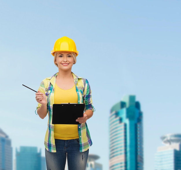 concept de réparation, de construction et d'entretien - femme souriante en casque avec presse-papiers