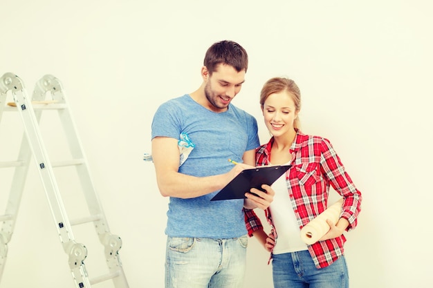 concept de réparation, de construction et de maison - couple souriant avec presse-papiers, rouleau de papier peint et échelle