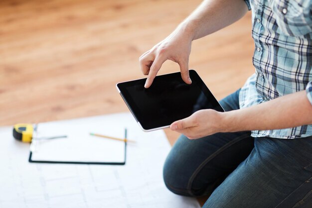 concept de réparation, de construction, de technologie et de maison - gros plan d'un homme avec tablette, plan et ruban à mesurer