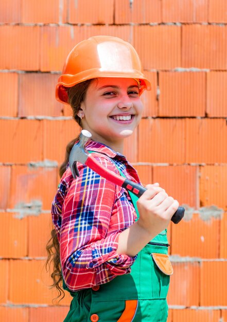 Concept de réparation enfant porter un casque sur le chantier de construction adolescente constructeur avec outil de construction marteau enfant sur la réparation des travaux concept de rénovation dans l'atelier charpentier professionnel occupé