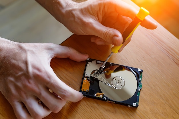 Un concept de réparation et de rénovation de disque dur, de disque dur. Le réparateur récupère les informations de données à partir d'un disque dur cassé.
