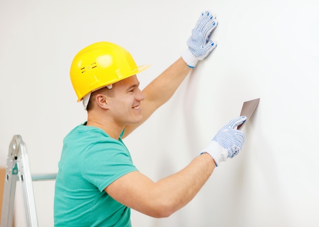 concept de réparation, de rénovation et de maison - homme souriant en casque faisant des rénovations à la maison