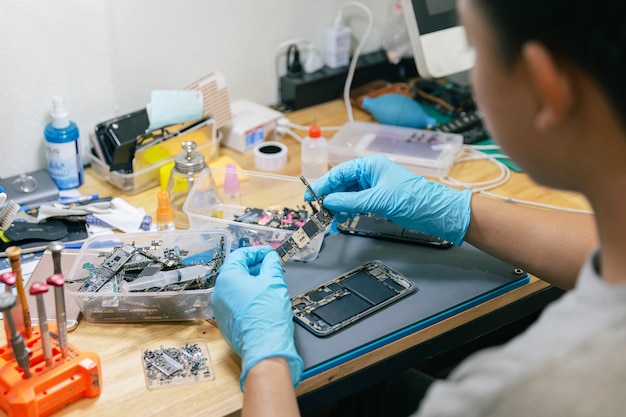 Concept de réparation de téléphone un réparateur choisissant la pièce électronique à assembler avec le téléphone portable avec les outils sur le bureau.