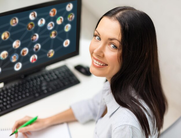 concept de réseautage, d'affaires et de technologie - femme d'affaires souriante étudiant avec ordinateur