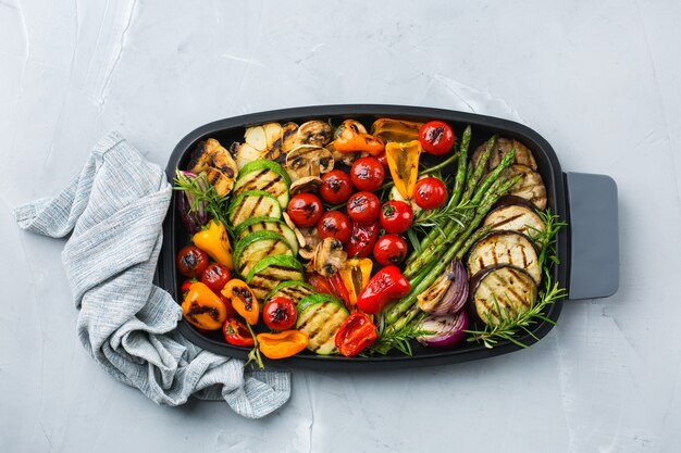 Concept de restauration végétalienne, végétarienne, saisonnière et estivale. Légumes grillés dans une casserole sur une table. Vue de dessus fond plat