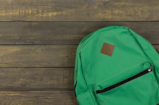 Concept de retour à l'école sac à dos vert sur fond en bois