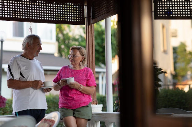 Concept de retraite Couple d'âge mûr buvant du café sur le porche Deux hommes et femmes âgés buvant du café et souriant ou discutant du plan futur après la retraite