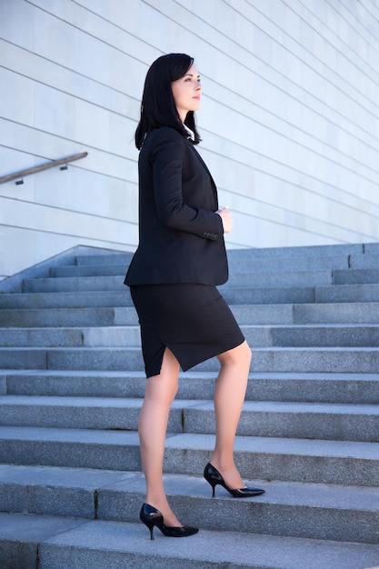 Concept de réussite jeune belle femme d'affaires debout dans les escaliers