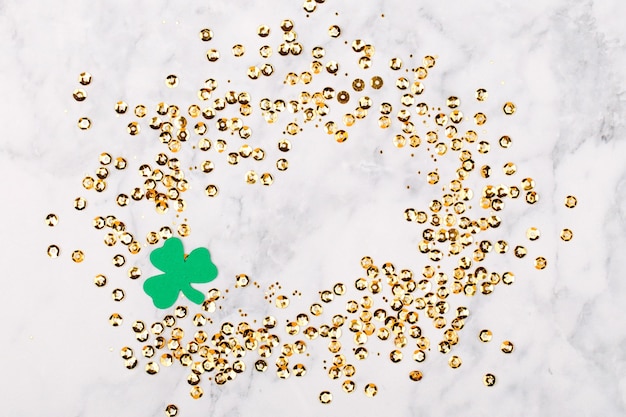 Concept de la Saint-Patrick. Fond avec trèfle leafi et cadre de confettis or. Modèle de maquette. Vue d'en-haut