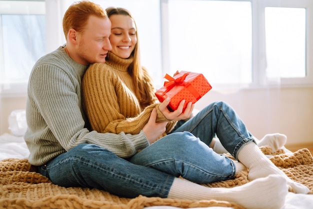 Concept de la Saint-Valentin Échange de cadeaux Jeune couple à la maison célébrant la Saint-Valentin