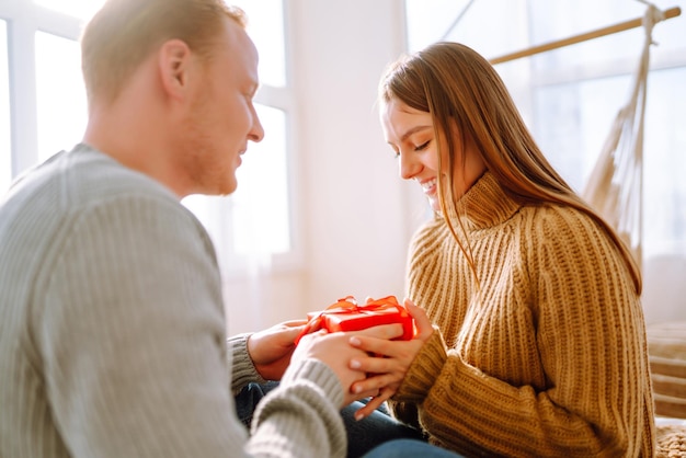 Concept de la Saint-Valentin Échange de cadeaux Jeune couple à la maison célébrant la Saint-Valentin