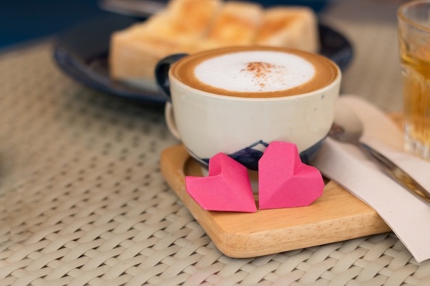 Concept de Saint Valentin, coeurs de papier rouge et une tasse de café sur un fond de bureau en bois