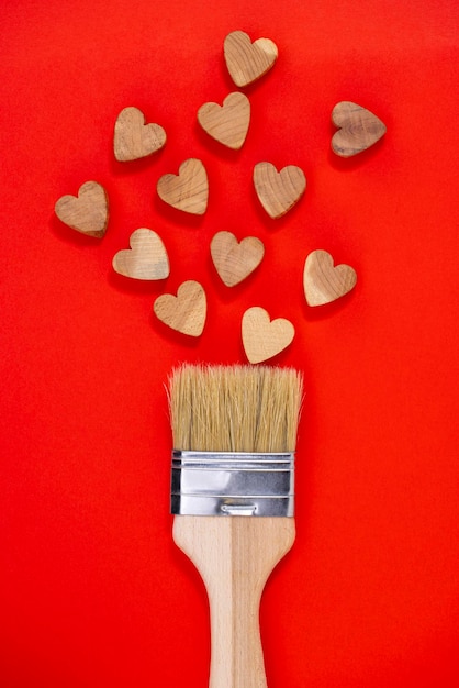 Concept de la Saint-Valentin Dessin au pinceau avec des coeurs en bois sur fond rouge