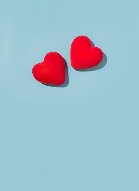 Photo concept de la saint-valentin avec deux cœurs rouges sur un fond bleu clair vue supérieure