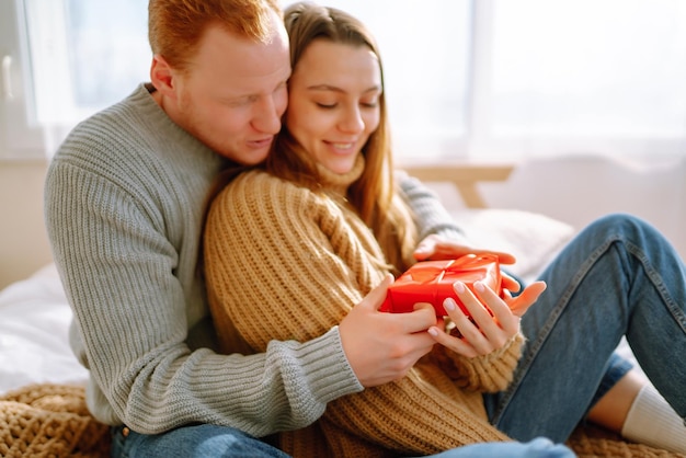 Concept de la Saint-Valentin Échange de cadeaux Jeune couple à la maison célébrant la Saint-Valentin