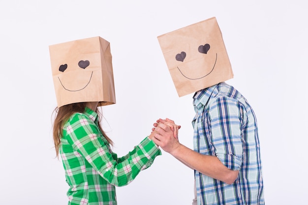 Concept de la Saint-Valentin - Jeune couple amoureux avec des sacs sur la tête sur fond blanc