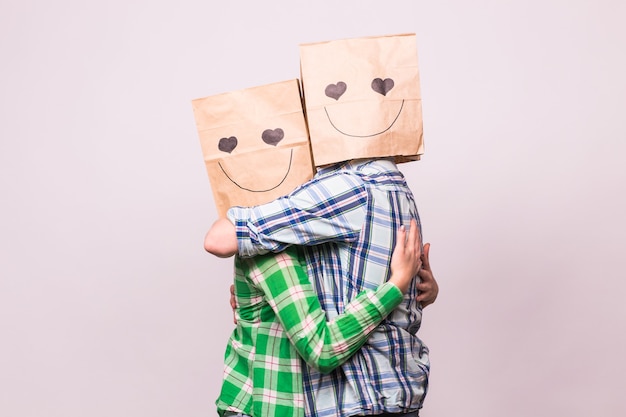 Concept de la Saint-Valentin - Jeune couple amoureux avec des sacs sur la tête sur fond blanc