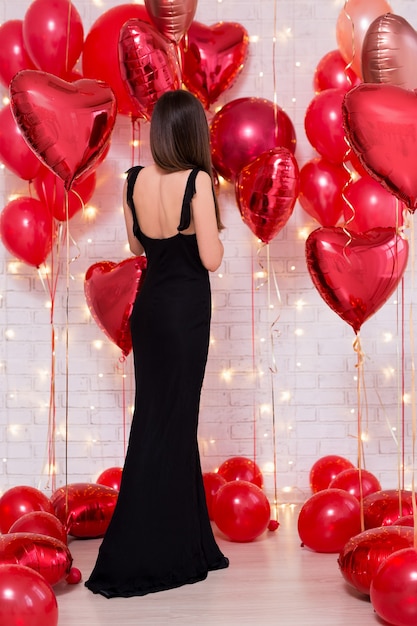 Concept de la Saint-Valentin vue arrière de la femme en robe noire avec des ballons rouges en forme de coeur