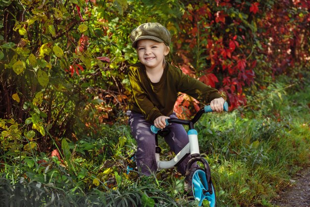 Le concept de la saison d'automne enfant se promène dans le parc d'automne se promène sur le vélo d'équilibre