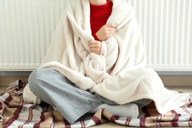 Concept de saison de chauffage avec une fille assise près du radiateur.