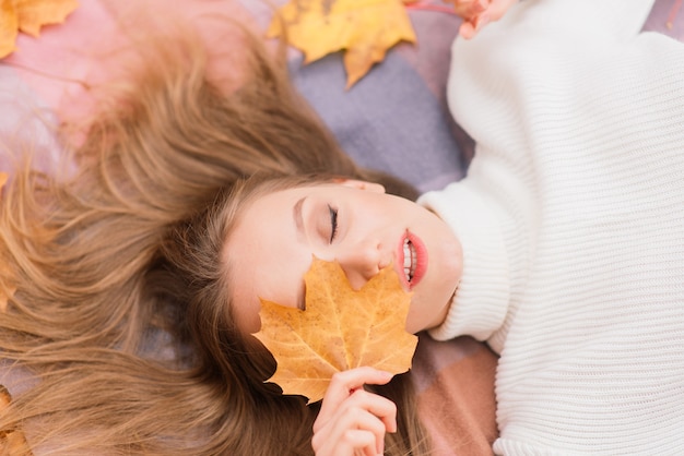 Concept de saison et de personnes - belle jeune femme avec des feuilles d'érable d'automne allongées sur le sol