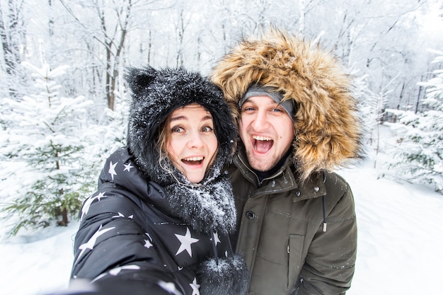 Concept de saison et de relation - Couple amusant prenant un selfie en hiver