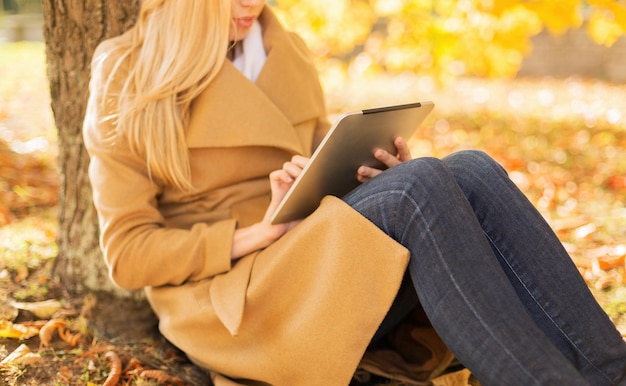 concept de saison, de technologie et de personnes - jeune femme avec un ordinateur tablette dans le parc d'automne