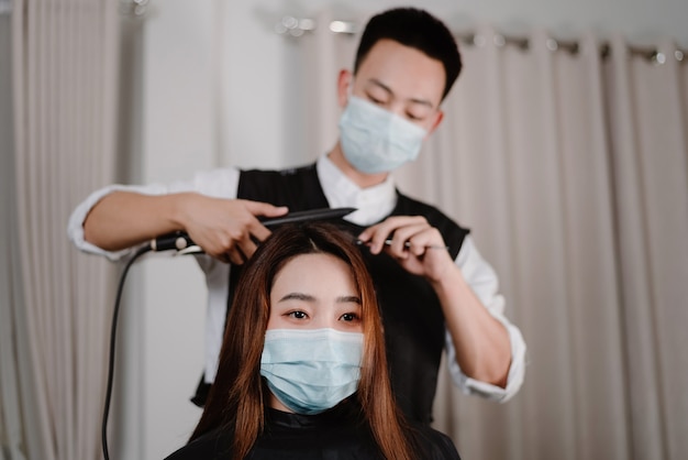 Concept de salon de coiffure à la fois coiffeur masculin et cliente portant un masque protecteur pendant le processus de coupe de cheveux.