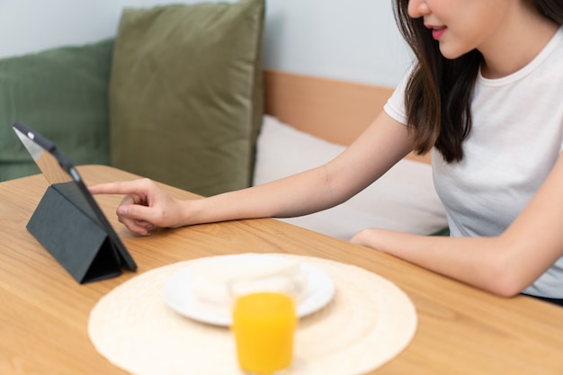 Concept de salon une fille aux cheveux longs assise dans le salon surfant sur internet avec son smartphone.